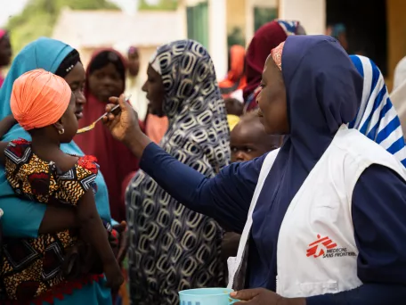 Maryam Muhammad, vedoucí podpory zdraví Kebbi, dává dítěti lžíci pokrmu Tom Brown. Nigérie, 2024. Foto: Georg Gassauer / Lékaři bez hranic 