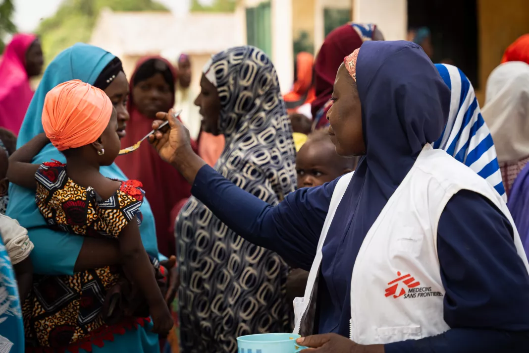 Maryam Muhammad, vedoucí podpory zdraví Kebbi, dává dítěti lžíci pokrmu Tom Brown. Nigérie, 2024. Foto: Georg Gassauer / Lékaři bez hranic 