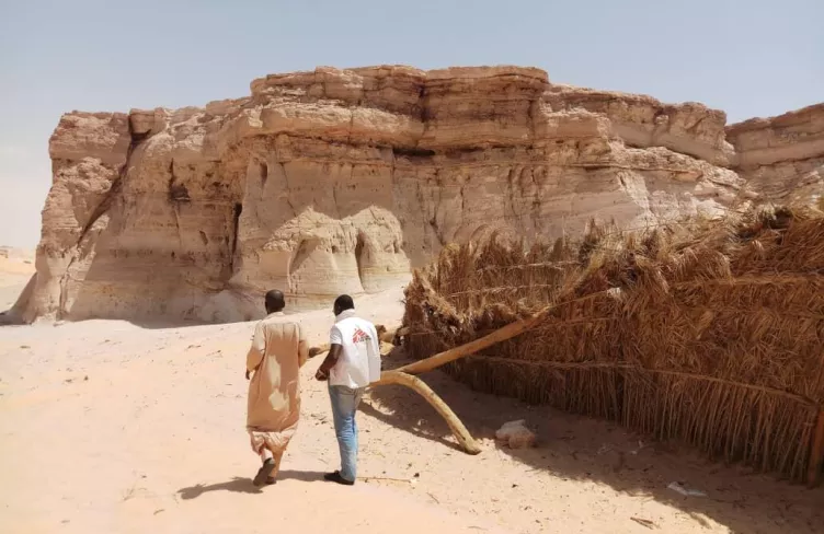 Člen týmu Lékařů bez hranic a další člověk ve skalnatém terénu, Niger, 2018. Foto: Innocent Kunywana / Lékaři bez hranic