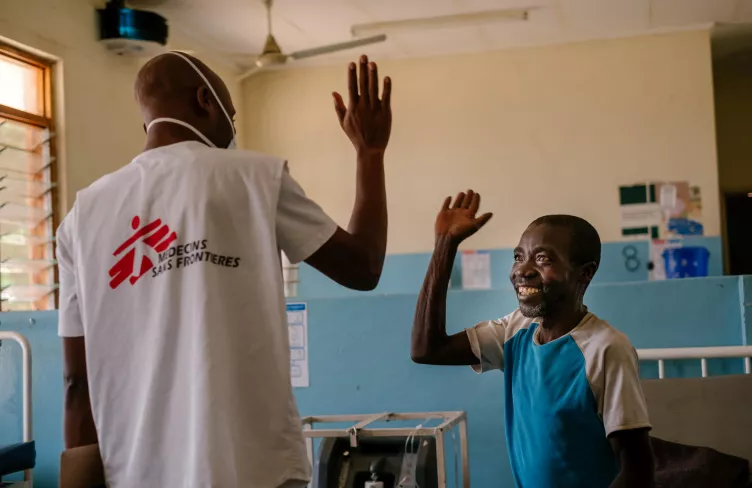 Muž a lékař se na sebe usmějí a jdou si plácnout, Malawi, 2019. Foto: Isabel Corthier / Lékaři bez hranic