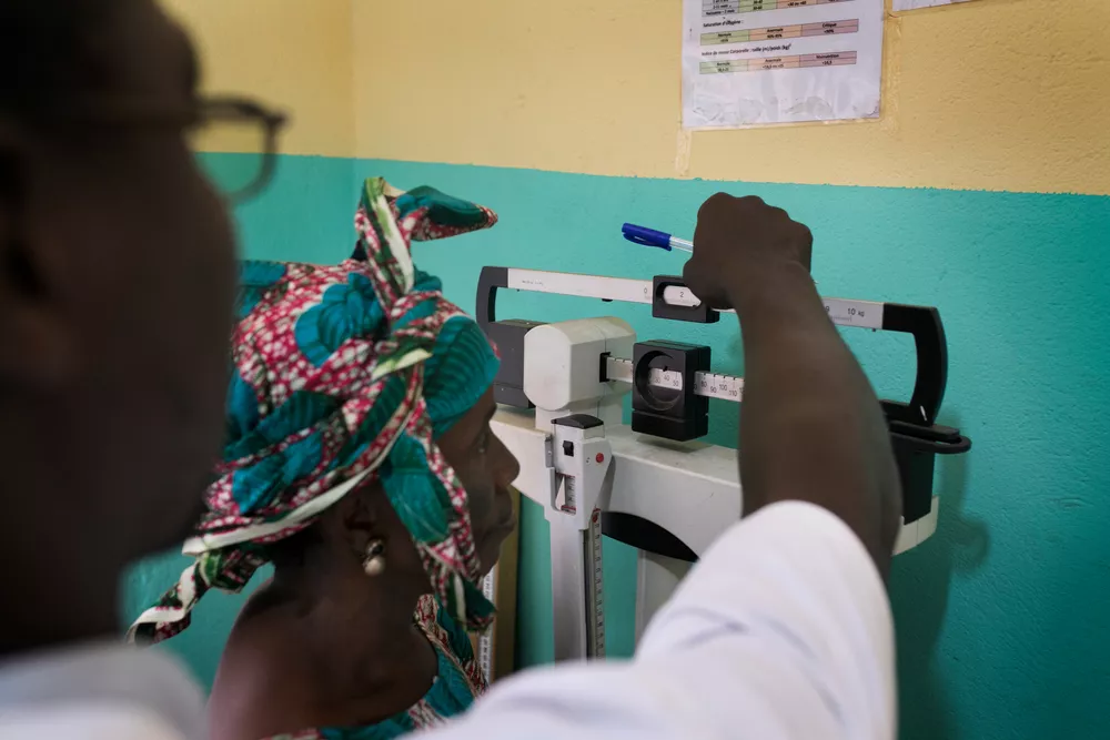 Zdravotník váží pacientku, Guinea, 2018. Foto: Albert Masias / Lékaři bez hranic