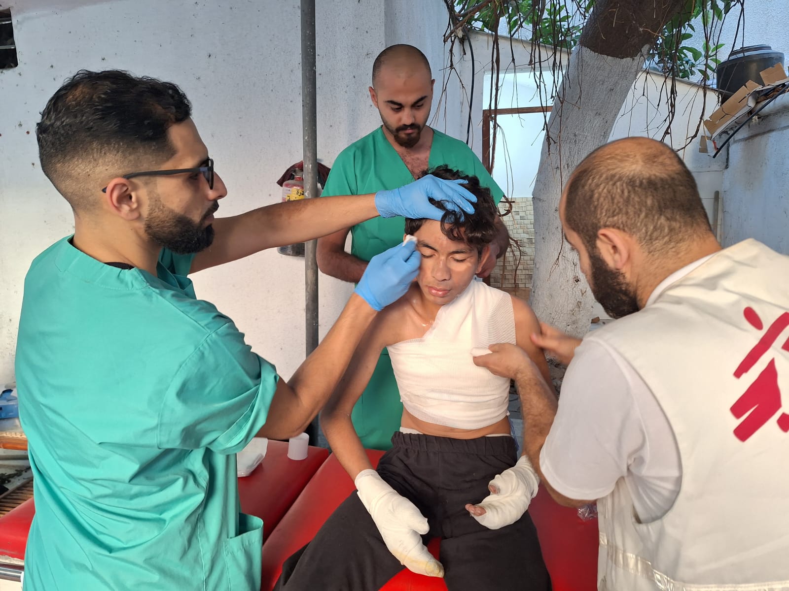 Zdravotníci ošetřují chlapce, Pásmo Gazy, 2023. 